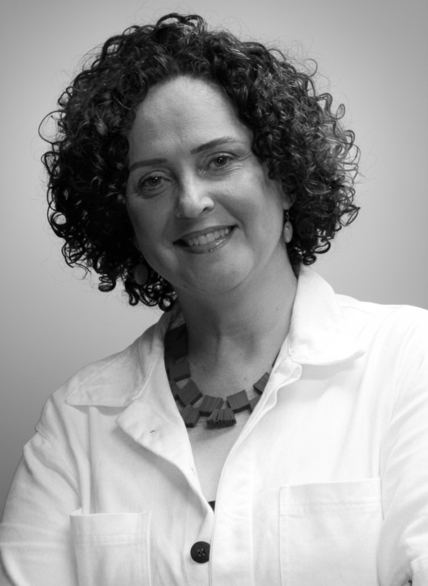 Mulher branca, com cabelos acima dos ombros. Está sorrindo.